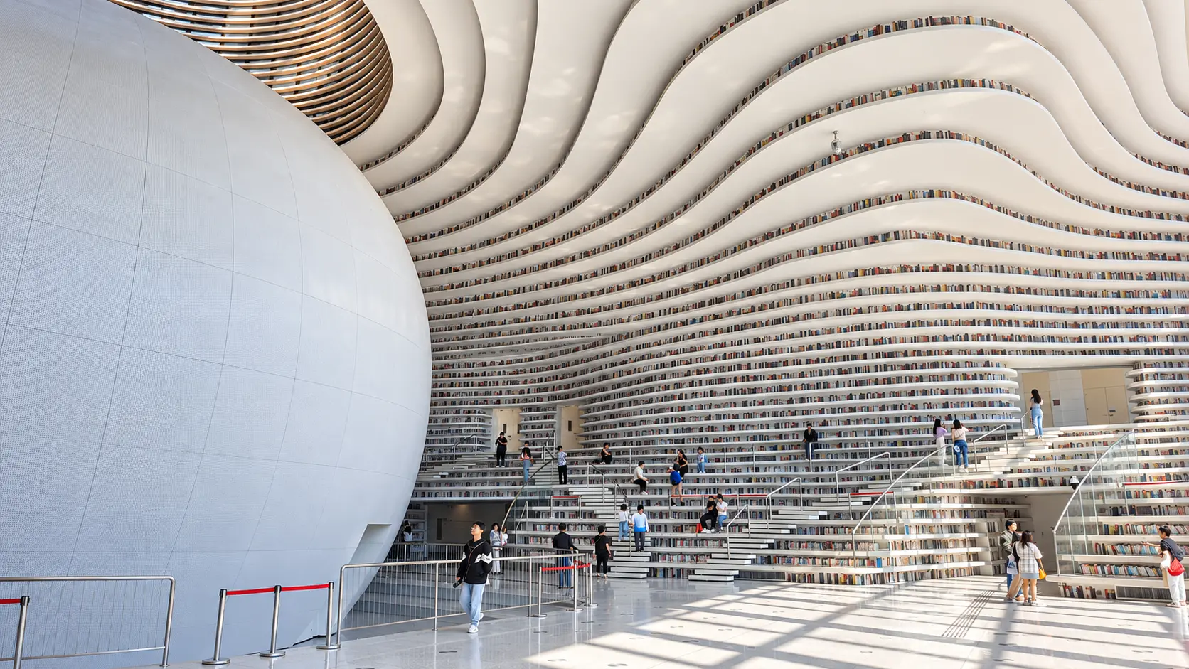 Bibliothèque de Tianjin Binhai : auditorium sphérique et rayonnages blancs aux lignes ondulantes
